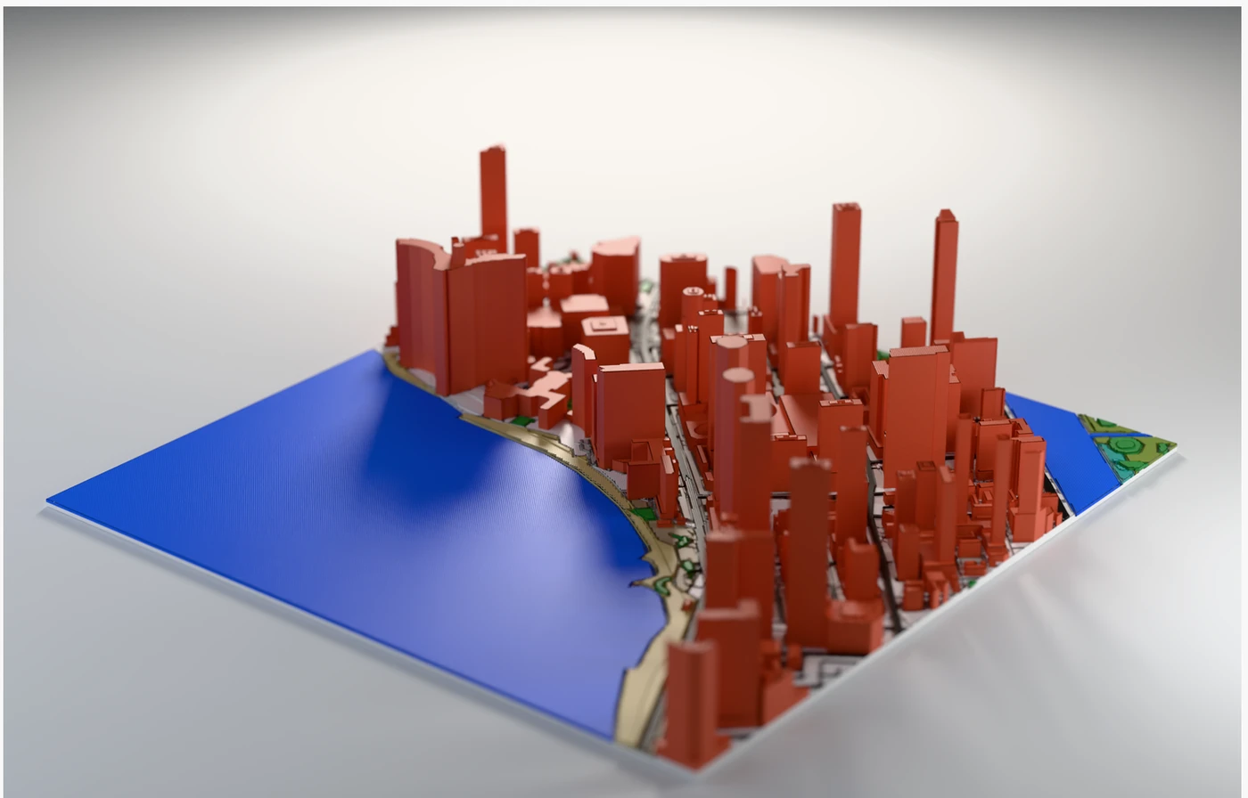 The same city relief model rendered as a printed object: red-orange buildings, a deep blue water plate, soft studio light and a cast shadow.